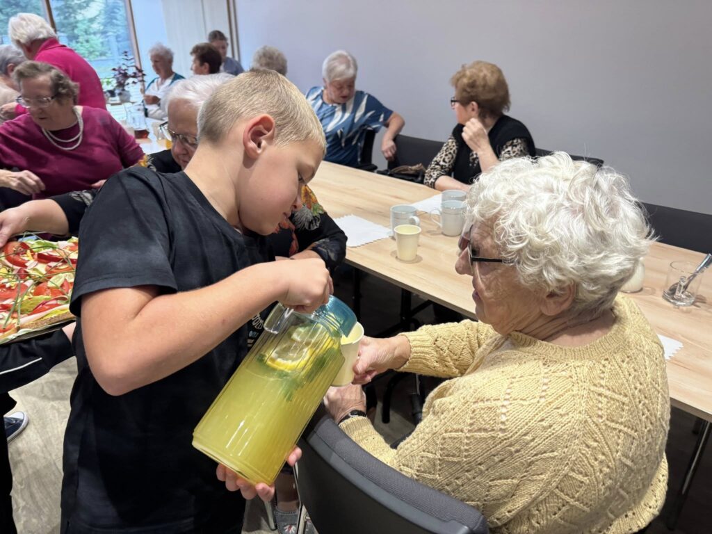 dzieci częstują seniorów kanapkami i lemoniadą