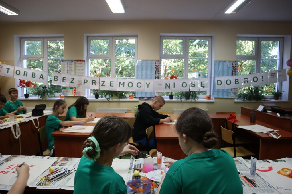 uczniowie malujący na torbach