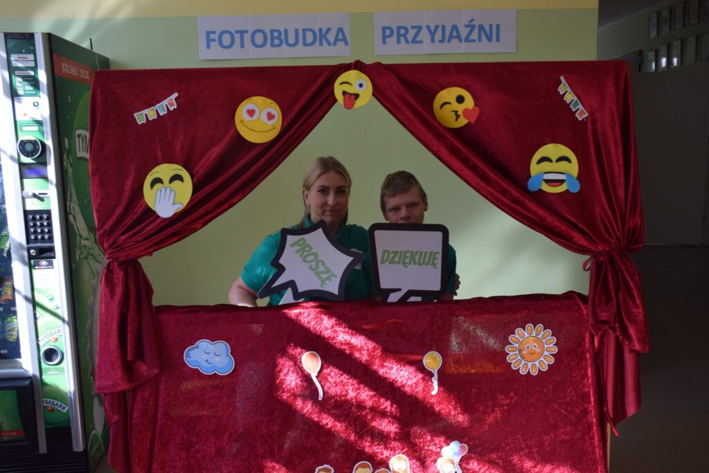 ludzie robiący sobie zdjęcia w fotobudce z fiszkami z dobrymi słowami