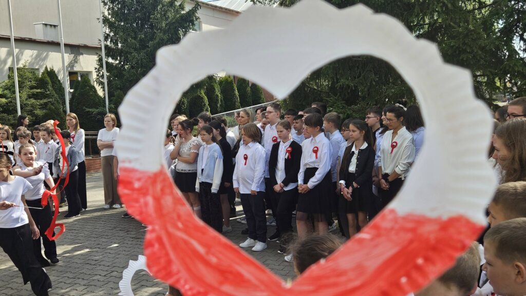 uczniowie w strojach galowych z kotylionami podczas apelu
