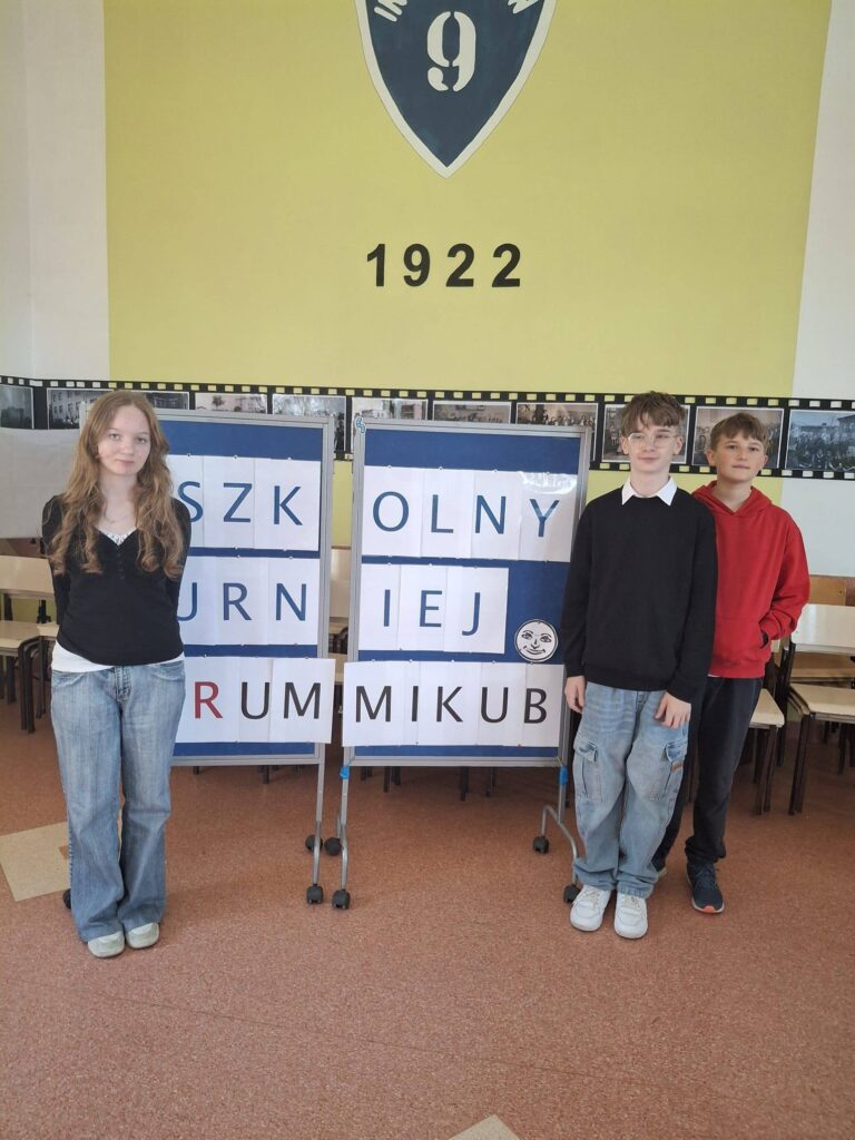 uczniowie z dyplomami w ręku za nimi gazetka dotycząca gry rummikub