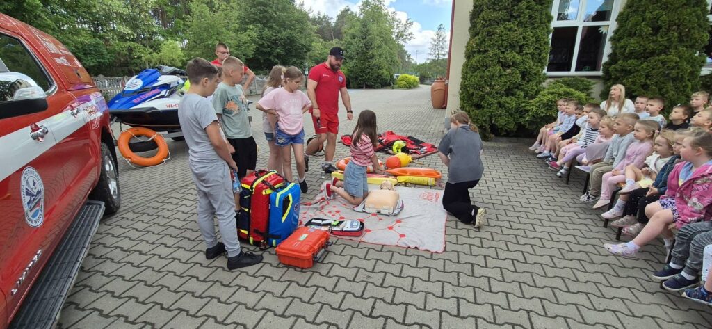 dzieci i ratownicy WOPR ;podczas prezentacji sprzętu ratowniczego i udzielania pierwszej pomocy