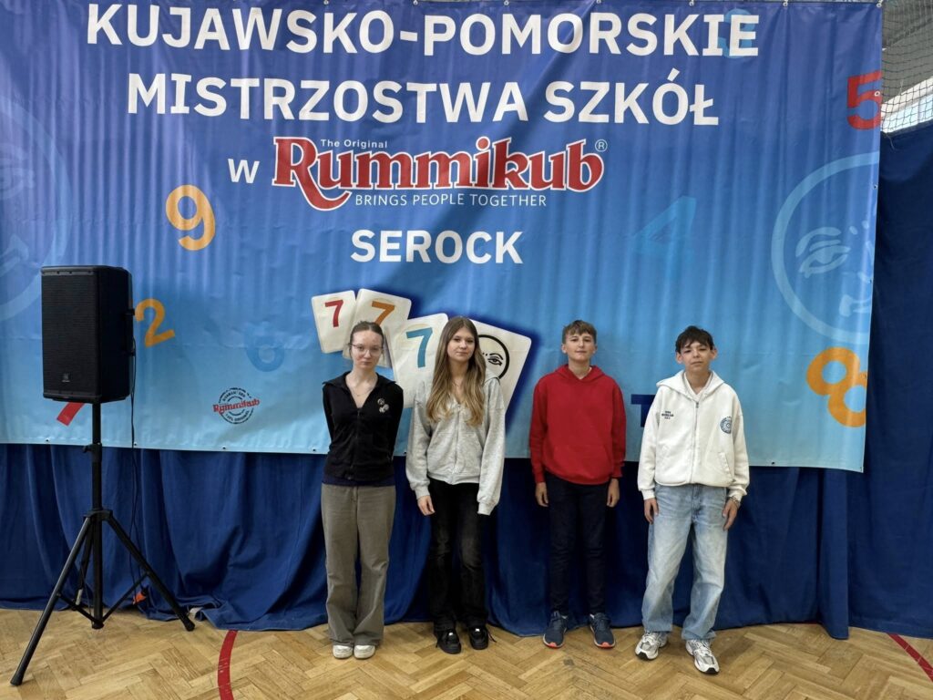 uczniowie na tle plakatu kujawsko - pomorskie mistrzostwa szkół Rummikub