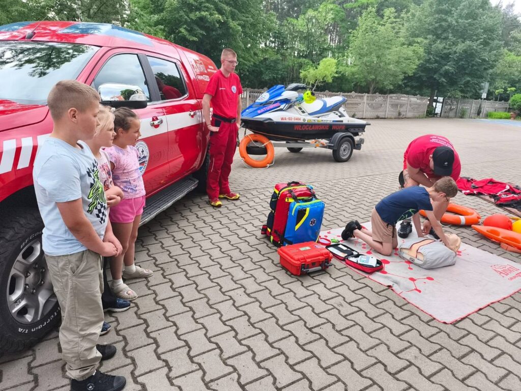 dzieci i ratownicy WOPR ;podczas prezentacji sprzętu ratowniczego i udzielania pierwszej pomocy