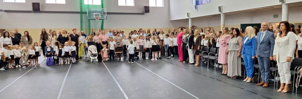 uczestnicy rozpoczęcia roku szkolnego stojący na baczność na hali sportowej