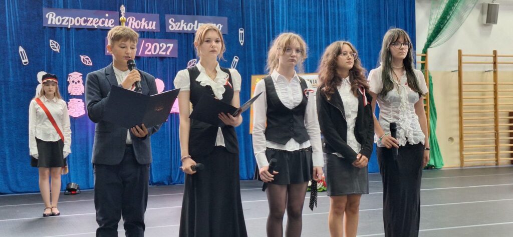 cztery dziewczyny i chłopiec na tle dekoracji na rozpoczęcie roku szkolnego