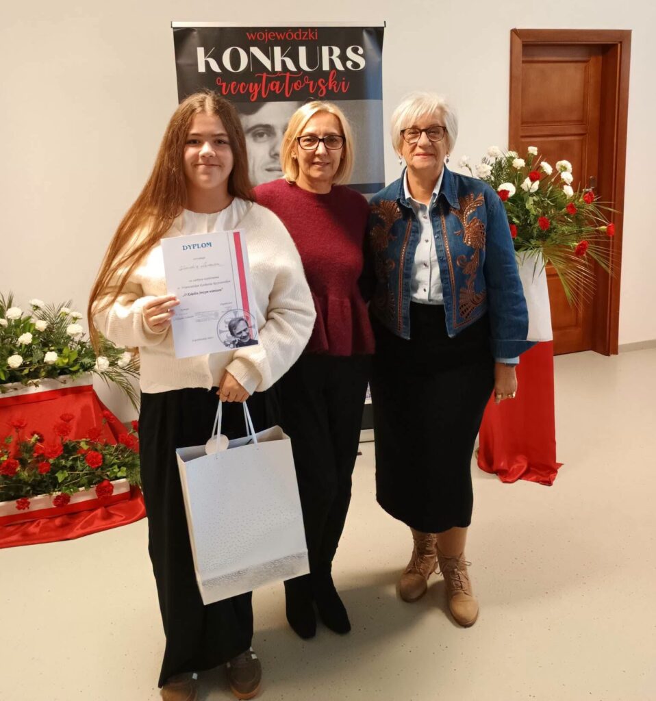 uczennica z dyplomem obok dwie panie z jury konkursu recytatorskiego